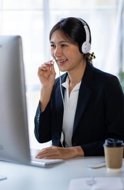 Smiling woman wearing a headset, speaking during a virtual meeting on a desktop computer
